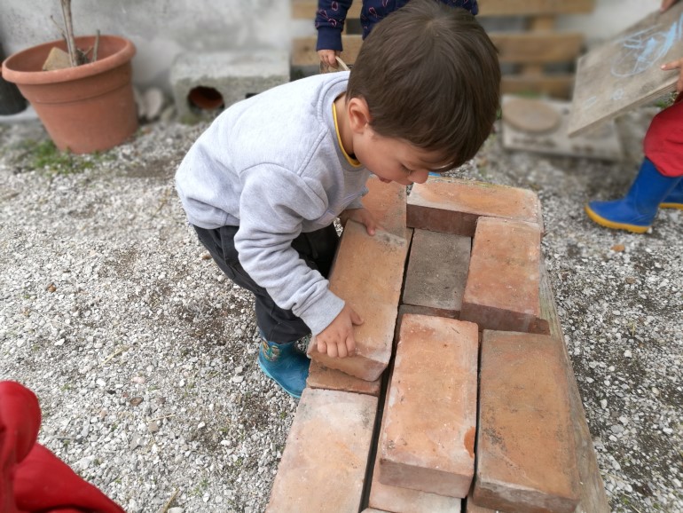 Uno dei bambini mentre costruisce un muretto
