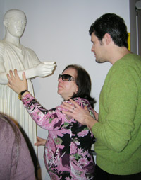Una guida del museo spiega a una visitatrice la tecnica per la lettura tattile delle sculture